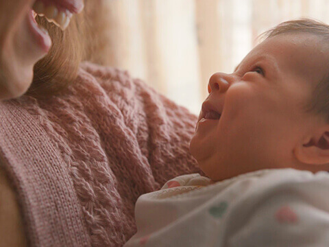 Mulher a sorrir para bebé - Bebé Medis Ageas Seguros