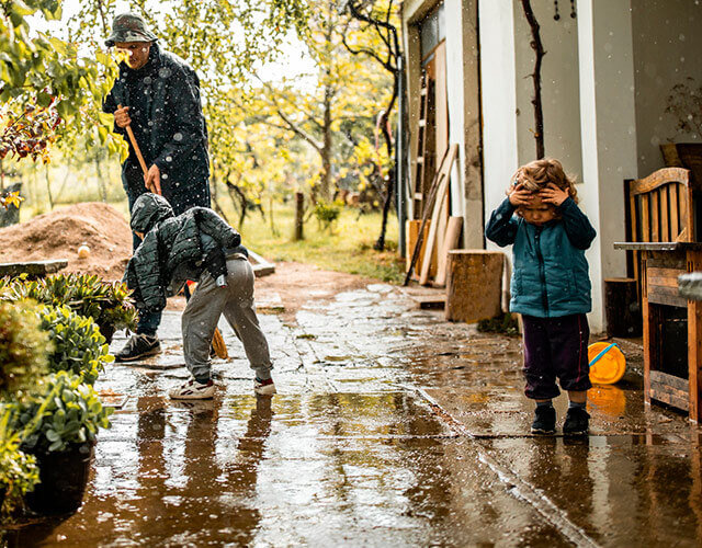 família a limpar a entrada de casa depois de inundações