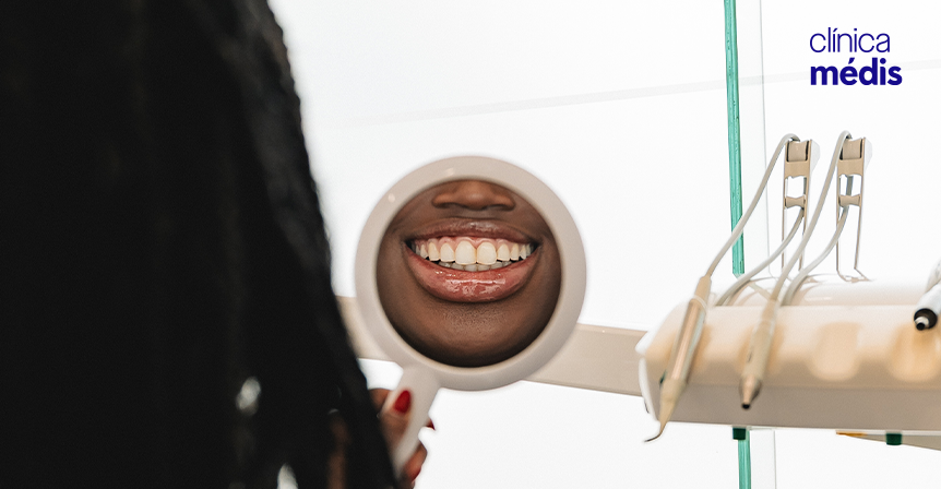 Senhora a sorrir para um espelho depois de tratamento na Clínica Médis